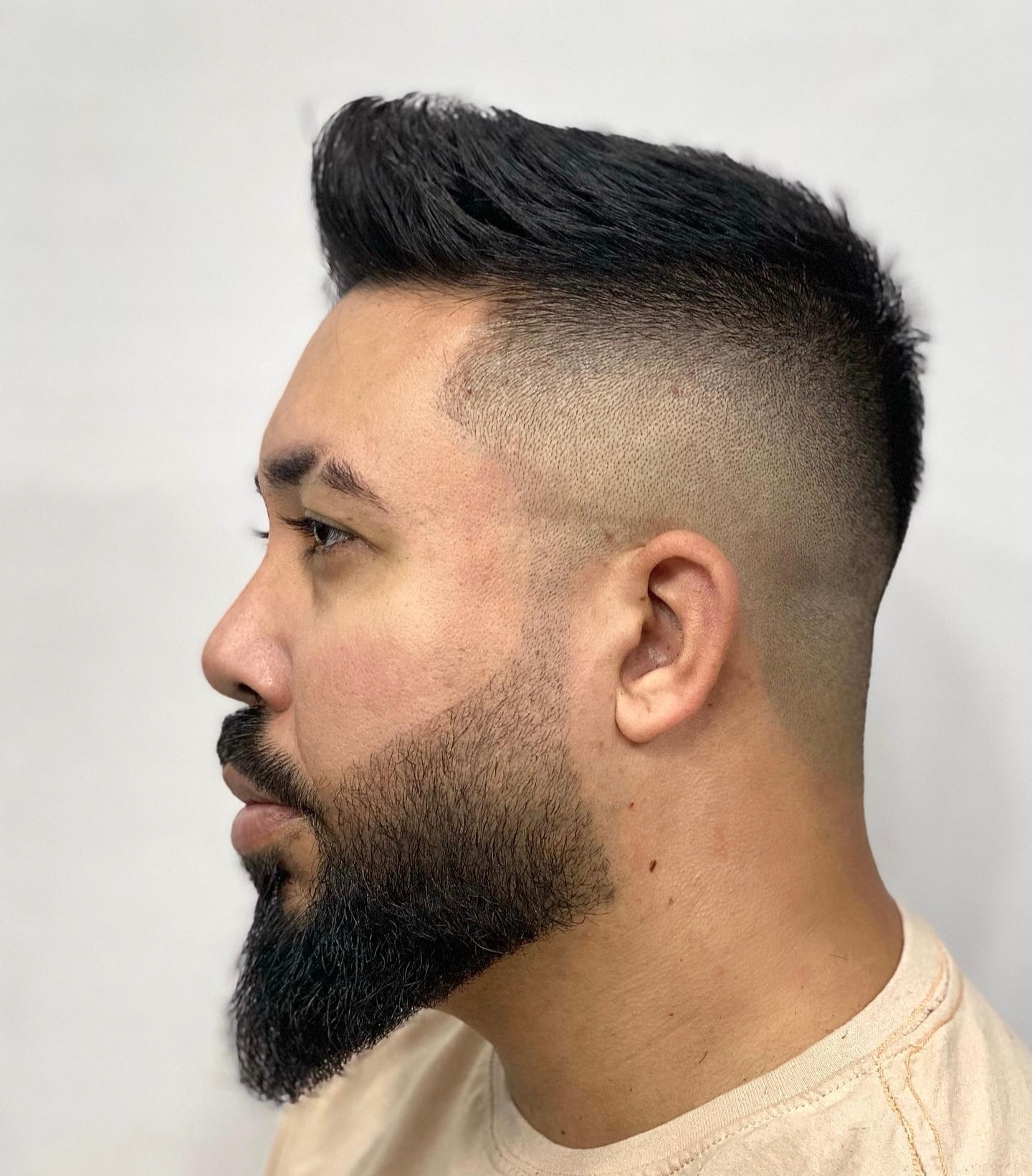 Zijprofiel van een klant met een korte fade en een volle, strak bijgewerkte baard